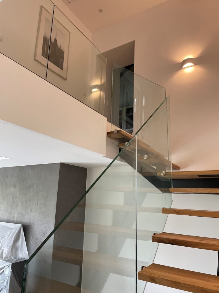 Modernes Treppendesign mit Glasgeländer und Holzstufen in stilvollem Wohnraum.